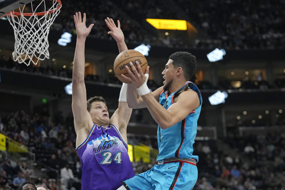 Phoenix Suns guard Devin Booker, right, goes to the basket as Utah Jazz center Walker Kessler (24) defends during the second half of an NBA basketball game Monday, March 27, 2023, in Salt Lake City. (AP Photo/Rick Bowmer)