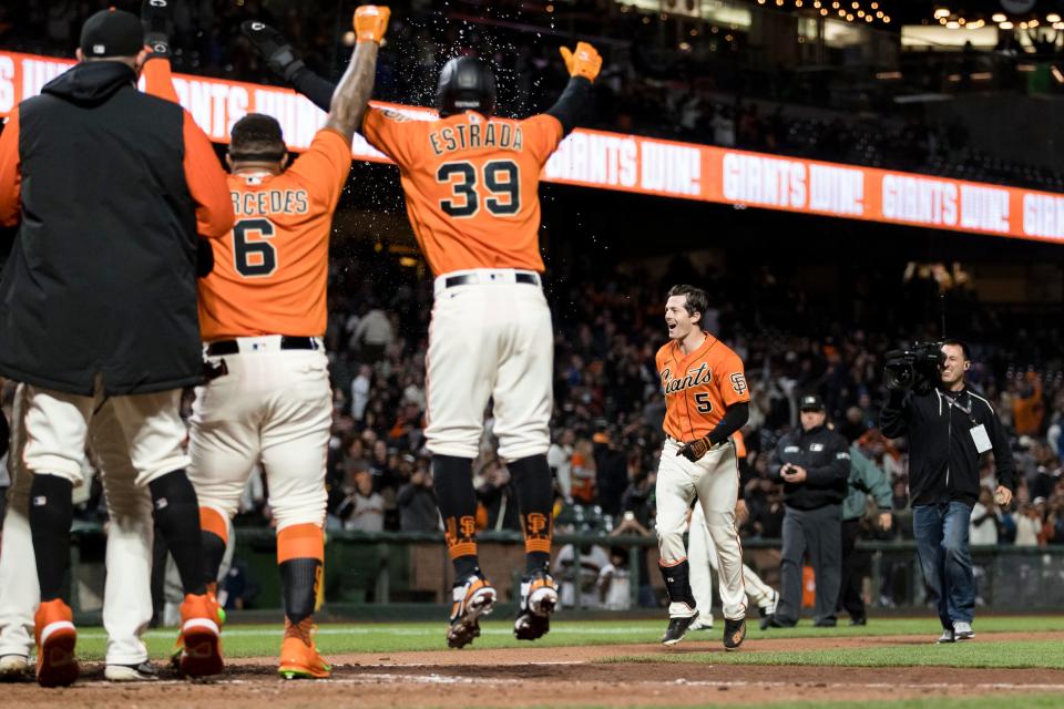 Giants players wait for Mike Yastrzemski at home plate after he belted a walk-off grand slam against Brewers closer Josh Hader with one out in the bottom of the ninth Friday night.