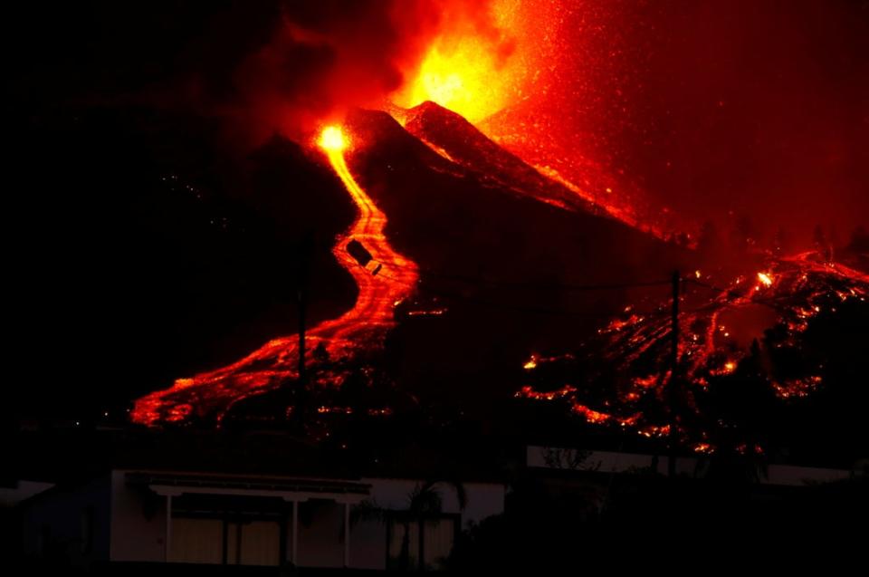 Lava flows next to a house on Sunday night (REUTERS)