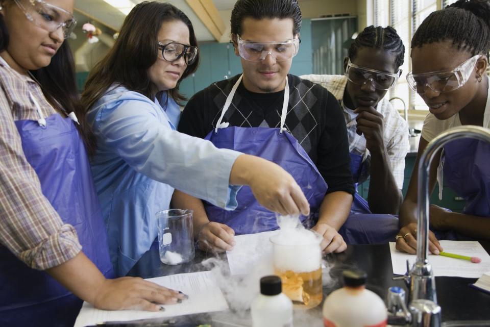 A group of diverse science students conduct an experiment on a lab bench.