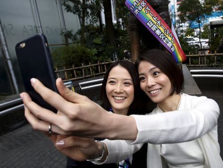 Hiroko Masuhara (L) and her partner Koyuki Higashi take 'selfie' pictures in front of the statue of famous Japanese dog Hachiko after the ward office issued the nation's first same sex partnership certificates in Tokyo, Japan, November 5, 2015.REUTERS/Yuya Shino