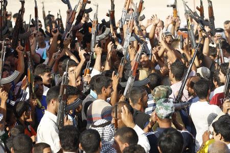 Volunteers, who have joined the Iraqi Army to fight against predominantly Sunni militants from the radical Islamic State of Iraq and the Levant (ISIL), gather with their weapons during a parade in the streets in Al-Fdhiliya district, eastern Baghdad June 15, 2014. REUTERS/Thaier Al-Sudani