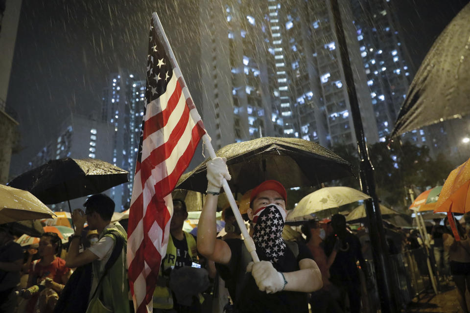 A protester waves a U.S. flag as hundreds of protesters gather outside Kwai Chung police station in Hong Kong, Tuesday, July 30, 2019. Protesters clashed with police again in Hong Kong on Tuesday night after reports that some of their detained colleagues would be charged with the relatively serious charge of rioting. (AP Photo/Vincent Yu)