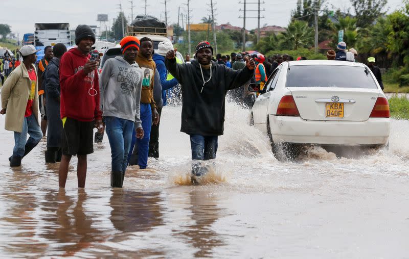 Volunteers direct traffic to clear the Athi River-Namanga highway that was affected after a seasonal river burst its banks following heavy rainfall in Kitengela municipality of Kajiado County