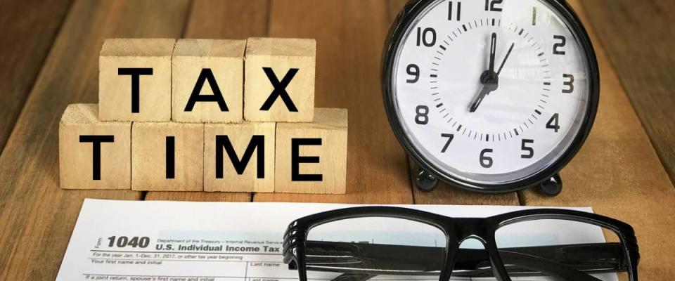 Tax-filling concept - ‘Tax time’ words on wooden blocks, pen, eyeglasses