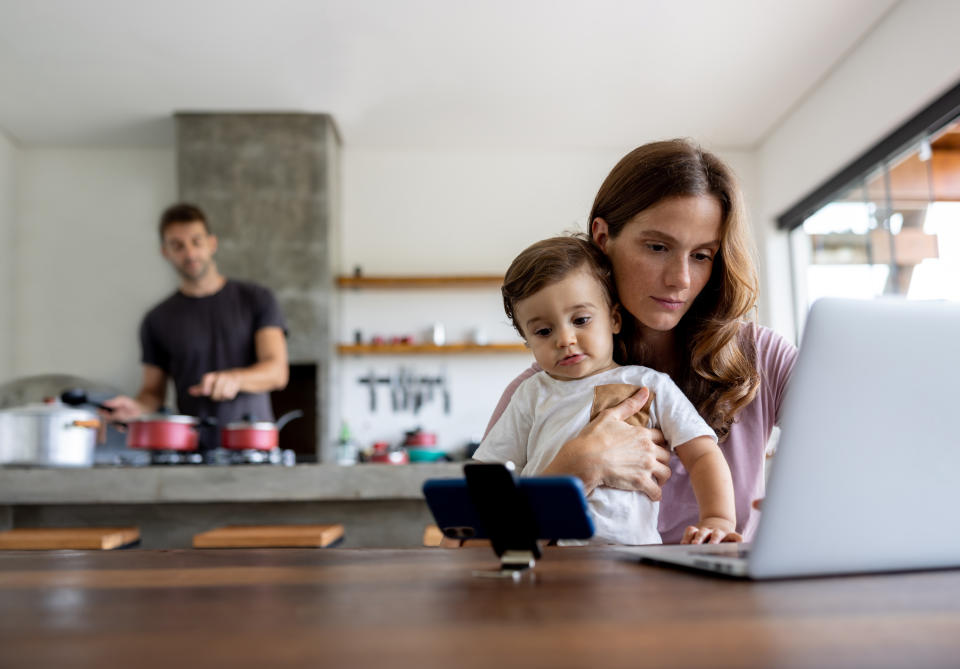 Mother working at home and distracting her son with videos on her cell phone