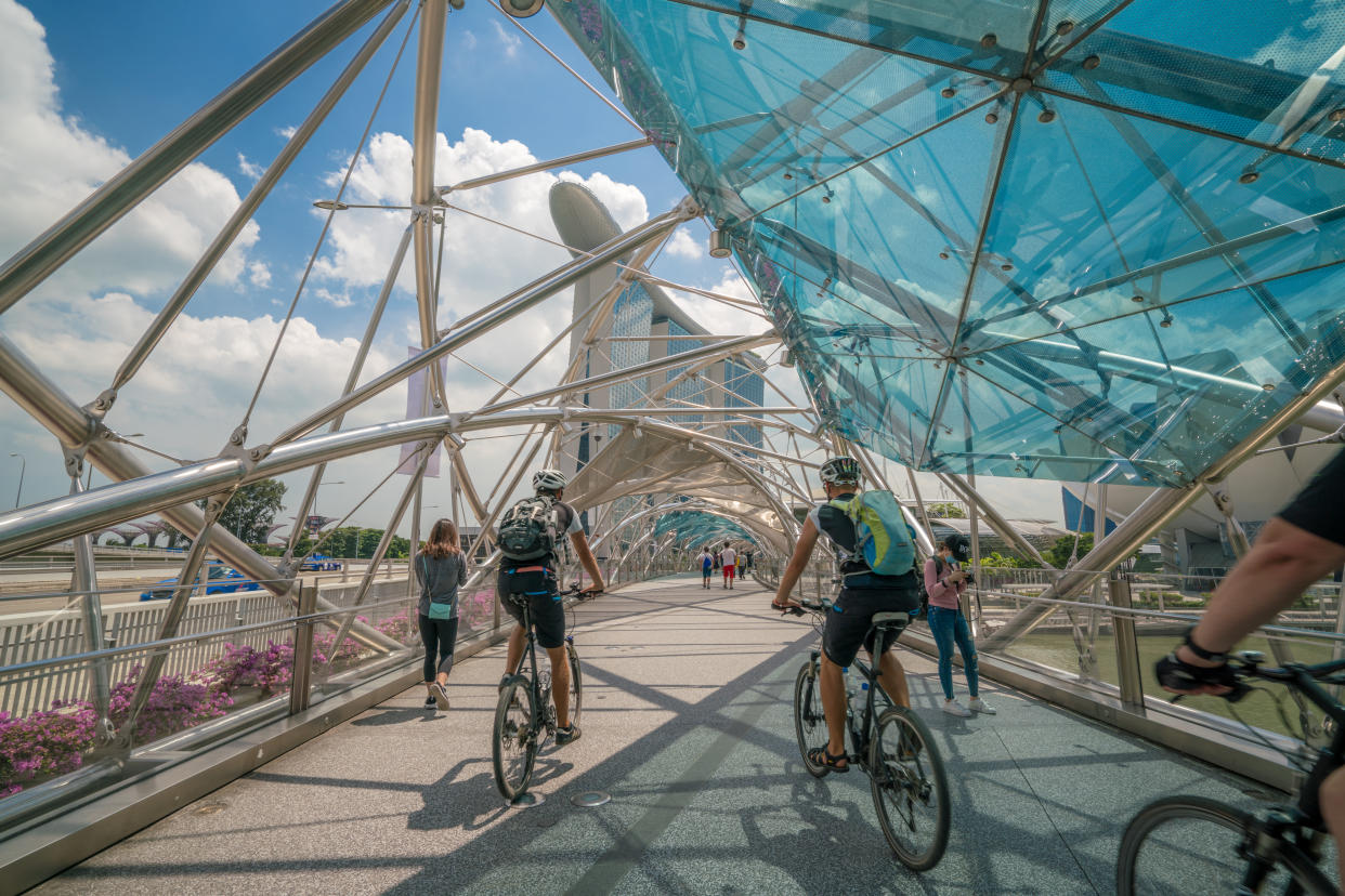 Cyclists riding bicycles on helix bridge with Marina Bay Sands.