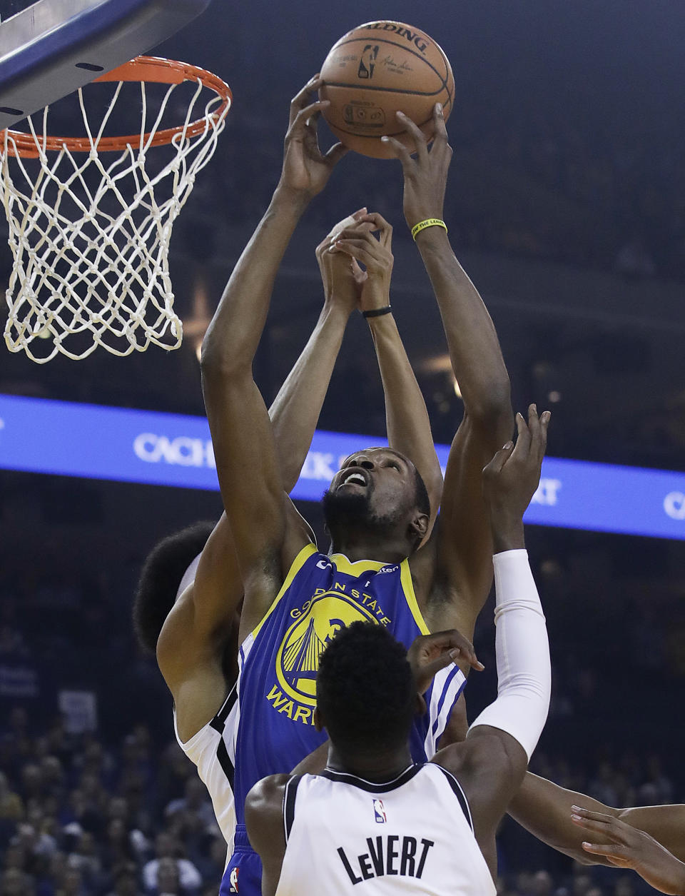 Golden State Warriors forward Kevin Durant, center, grabs a rebound between Brooklyn Nets guard Caris LeVert, bottom, and center Jarrett Allen during the first half of an NBA basketball game in Oakland, Calif., Saturday, Nov. 10, 2018. (AP Photo/Jeff Chiu)