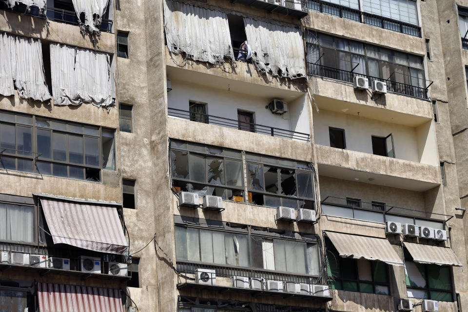 A woman hangs laundry at the 11th-floor building that houses the media office in a stronghold of the Lebanese Hezbollah group, in a southern suburb of Beirut, Lebanon, Sunday, Aug. 25, 2019. Two Israeli drones crashed in a Hezbollah stronghold in the Lebanese capital overnight without the militants firing on them, a spokesman for the group said Sunday, saying the first fell on the roof of a building housing Hezbollah's media office while the second landed in a plot behind it. (AP Photo/Bilal Hussein)