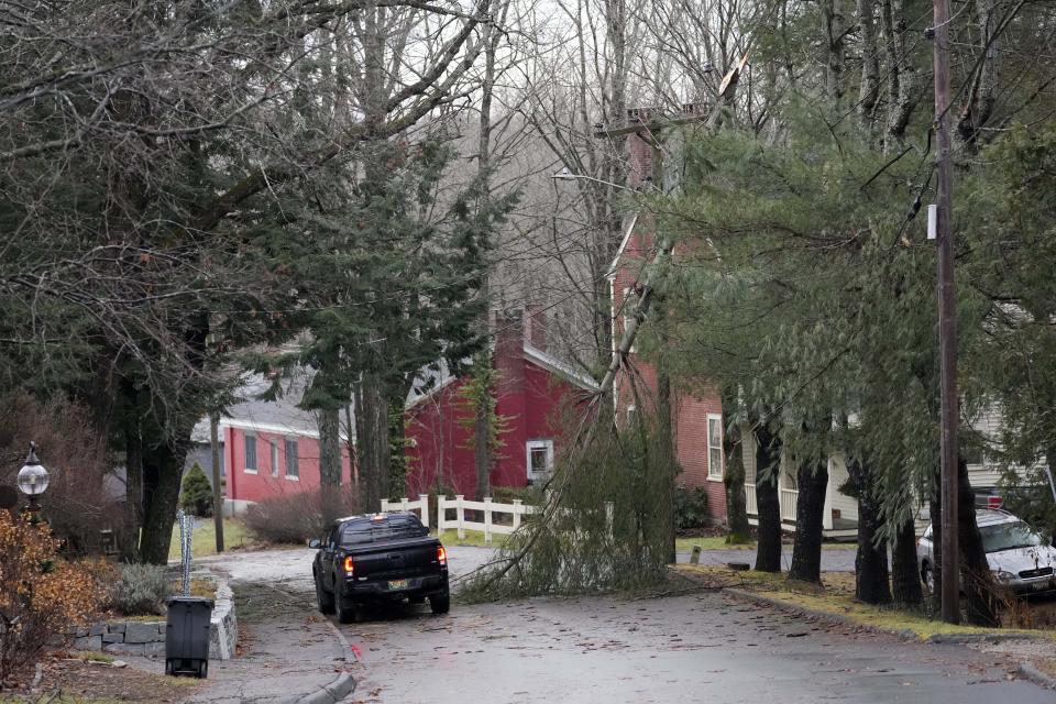 A motorist maneuvers around a broken tree limb, Tuesday, Dec. 19, 2023, in Hallowell, Maine. Thousands of people remain without power following Monday's severe storm. (AP Photo/Robert F. Bukaty)