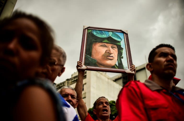 A pro-government activist holds a portrait depicting late Venezuelan President Hugo Chavez during a demo to show their support to the government of Venezuelan President Nicolas Maduro and against US President Donald Trump