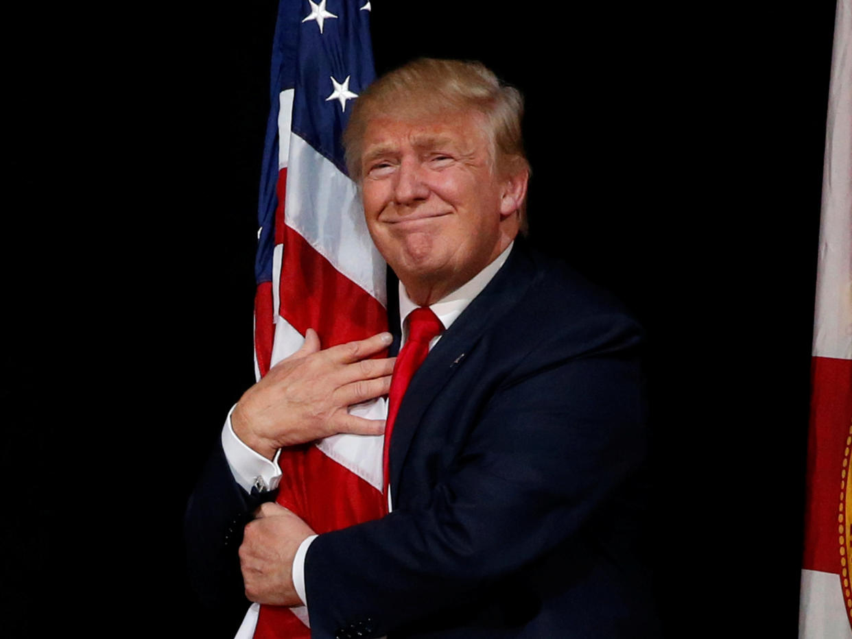 Donald Trump hugs a US flag at a rally with supporters in Tampa, Florida, in 2016: REUTERS