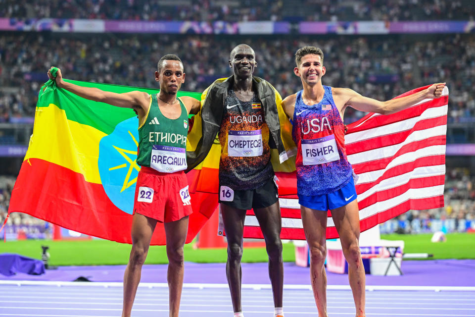 PARIS, FRANCE - AUGUST 02: Gold medalist Joshua Cheptegei (C) of Uganda, silver medalist Berihu Aregawi (L) and bronze medalist Grant Fisher (R) of United States celebrate after competing the Men's 10,000m Final on day seven of the Olympic Games Paris 2024 at Stade de France on August 02, 2024 in Paris, France. (Photo by Mehmet Murat Onel/Anadolu via Getty Images)