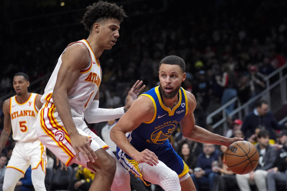 Golden State Warriors guard Stephen Curry (30) tries to gets past Atlanta Hawks forward Jalen Johnson (1) in the first half of an NBA basketball game Saturday, Feb. 3, 2024, in Atlanta. (AP Photo/John Bazemore) Warriors