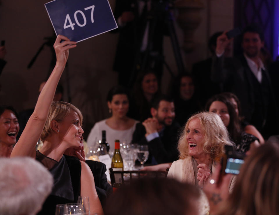 Charlize Theron, left, is seen bidding during the auction at the 3rd Annual Sean Penn & Friends HELP HAITI HOME Gala on Saturday, Jan. 11, 2014 at the Montage Hotel in Beverly Hills, Calif. (Photo by Colin Young-Wolff /Invision/AP)