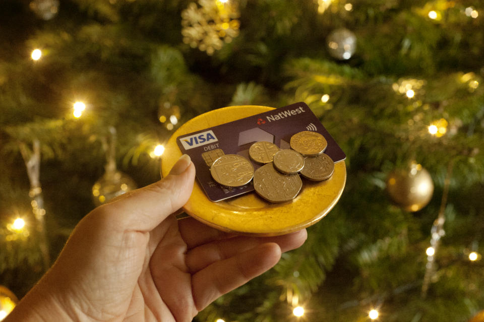 First person perspective showing payment being made with a debit card & a cash tip, against a festive backdrop of a decorated Christmas Tree. Photo: Tracey Packer/Getty