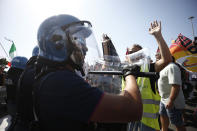 Police face Alitalia workers staging a protest at the Rome Leonardo Da Vinci international airport in Fiumicino, Friday, Sept. 24, 2021. Alitalia, which has been in the red for more than a decade, is due to formally exit the airline market next month and be replaced by a new national carrier ITA, or Italy Air Transport. The European Commission has given the go-ahead to a 1.35 billion euro ($1.58 billion) injection of government funding into the new airline, but ITA is only planning to hire around a quarter of the estimated 10,000 Alitalia employees.(Cecilia Fabiano/LaPresse via AP)