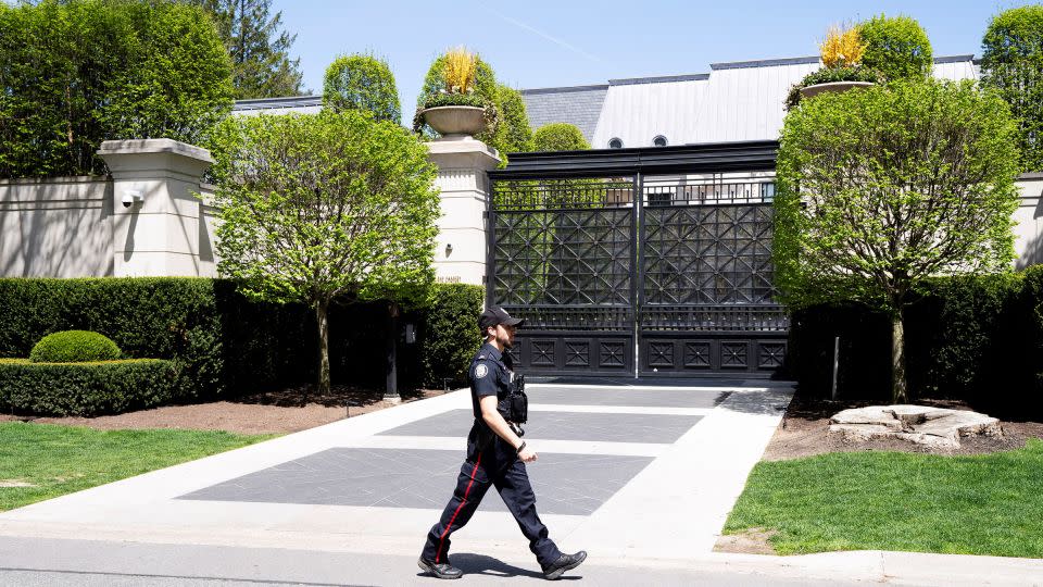 A Toronto police officer walking outside of Drake's mansion in Toronto after a security guard was shot outside the home on Tuesday. - Arlyn McAdorey/Reuters