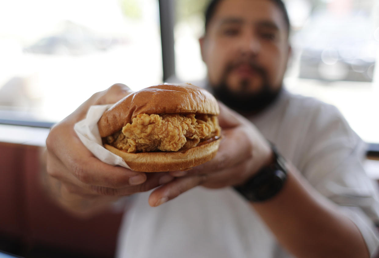 Randy Estrada holds up his chicken sandwiches at a Popeyes, Thursday, Aug. 22, 2019, in Kyle, Texas. After Popeyes added a crispy chicken sandwich to their fast-fast menu, the hierarchy of chicken sandwiches in America was rattled, and the supremacy of Chick-fil-A and others was threatened. It’s been a trending topic on social media, fans have weighed in with YouTube analyses and memes, and some have reported long lines just to get a taste of the new sandwich. (AP Photo/Eric Gay)