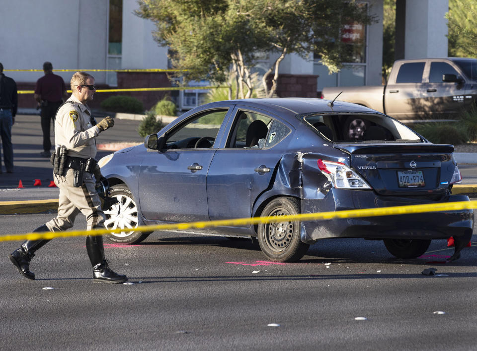 Las Vegas police investigate a suspect's vehicle after a Las Vegas policeman was fatally shot on Thursday, Oct. 13, 2022, in Las Vegas. Las Vegas police say a veteran patrol officer is dead after being shot during an exchange of gunfire with a man who was later arrested. Clark County Sheriff Joe Lombardo told reporters that Officer Truong Thai was fatally wounded early Thursday after he and a partner stopped a vehicle while answering a domestic violence call east of the Las Vegas Strip. (Bizuayehu Tesfaye Las Vegas Review-Journal via AP)