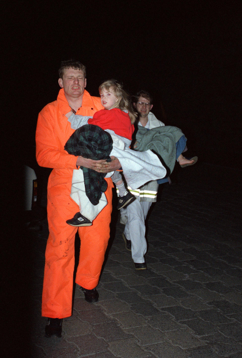 A rescuer holds a girl, survivor of the sinking of the British ferry 