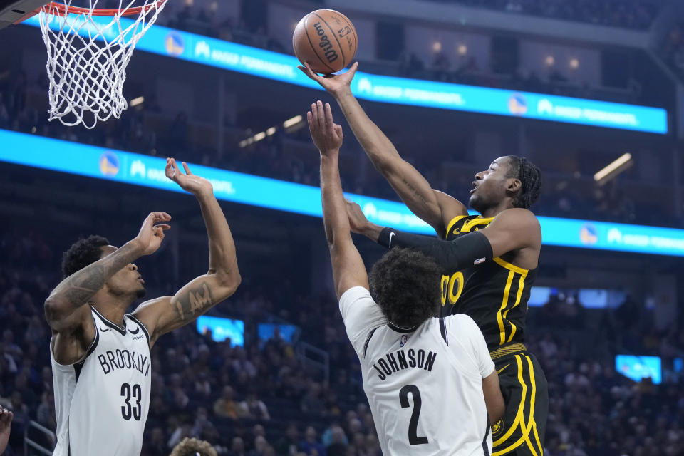 Golden State Warriors forward Jonathan Kuminga, right, shoots against Brooklyn Nets forward Cameron Johnson (2) and center Nic Claxton (33) during the first half of an NBA basketball game in San Francisco, Saturday, Dec. 16, 2023. (AP Photo/Jeff Chiu)