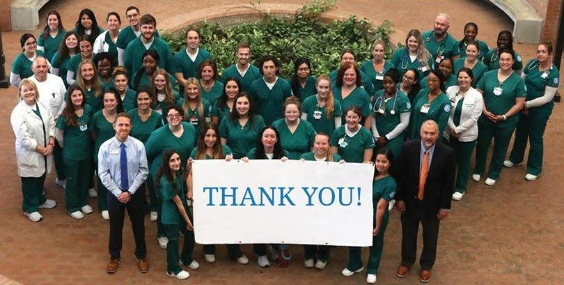 Students and faculty in the Bob and Carol Allen School of Nursing at Daytona State College posed with this thank-you sign acknowledging gifts from Halifax Health and AdventHealth hospitals, as well as a new state matching grant program. The $3.8 million will be used to boost student success in an effort to raise the number of nursing graduates.