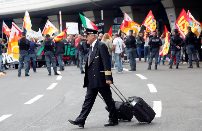 An Alitalia crew member walks past Alitalia employees who take part in a strike at Fiumicino international airport in Rome, Italy April 5, 2017. REUTERS/Remo Casilli     