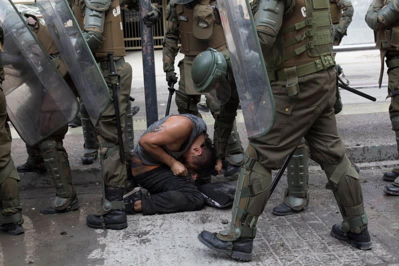 A demonstrator is pulled from his hair while is detained by riot policemen during a protest against Chile's government in Santiago