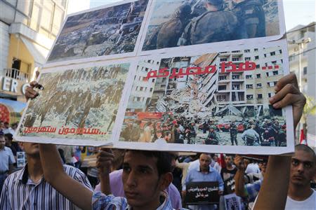 An activist holds up a placard, which reads: "You will be defeated. This is your destiny", during a sit-in near the U.S. embassy in Awkar, north of Beirut, against potential U.S. strikes on Syria September 6, 2013. U.S. officials ordered non-emergency personnel and their family members out of Lebanon on Friday "due to threats," the U.S. embassy in Beirut said in statement. The picture on the bottom right of the placard shows a scene from the 1983 suicide bombing of the U.S. embassy in Beirut. REUTERS/Mohamed Azakir