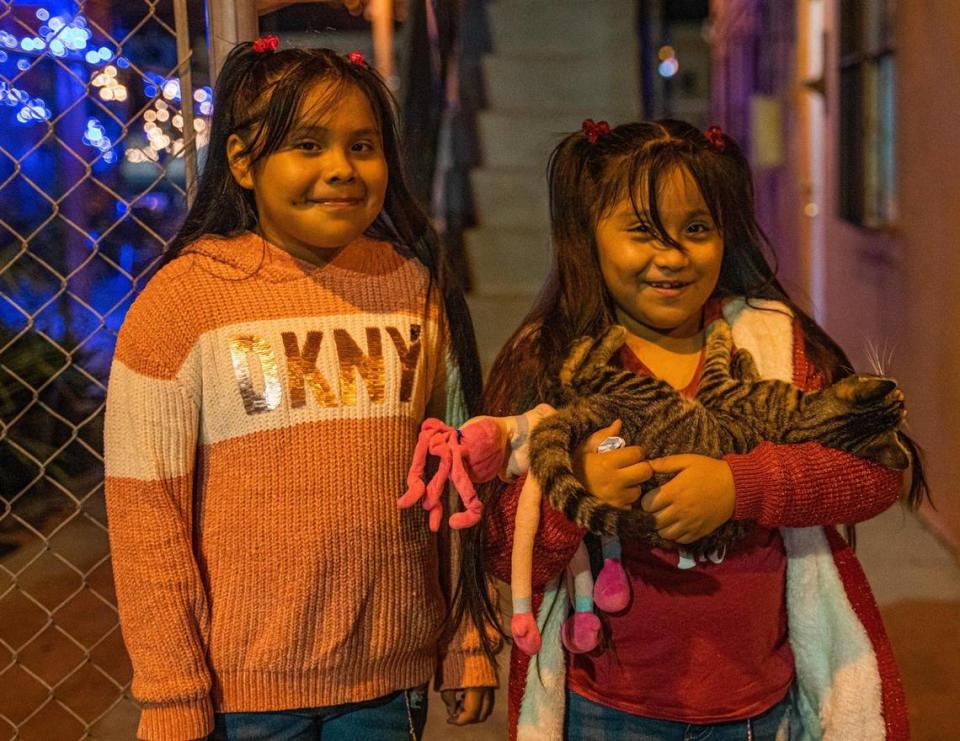 Brenda y Abigail Arreguín posan con un gato en el pasillo del edificio donde viven en Homestead. Las niñas necesitan ropa, zapatos y otros artículos que el padre no puede comprar porque su salario es muy bajo.