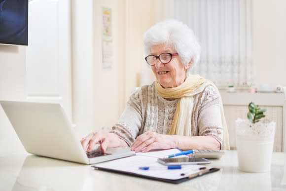 Smiling senior woman typing on laptop