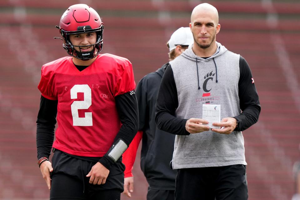 Cincinnati Bearcats quarterback Brendan Sorsby (2), left, smiles during spring football practice next to quarterbacks coach Pete Thomas.