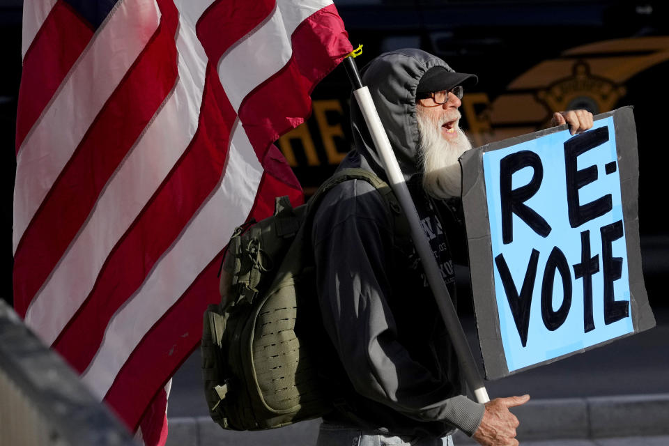 A man protests outside the Maricopa County Board of Supervisors auditorium prior to the board's general election canvass meeting, Monday, Nov. 28, 2022, in Phoenix. (AP Photo/Matt York)