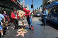 Gregg Donovan, left, former ambassador of Beverly Hills and a Spiderman character impersonator, honor actor Olivia Newton-John with flowers on her Hollywood Walk of Fame star in Los Angeles Monday, Aug. 8, 2022. Olivia Newton-John, the Grammy-winning superstar who reigned on pop, country, adult contemporary and dance charts with such hits as "Physical" and "You're the One That I Want" has died. She was 73. (AP Photo/Damian Dovarganes)