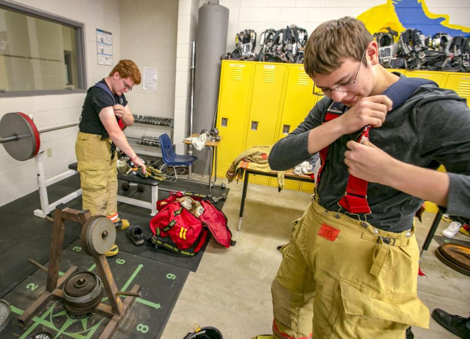 John Lawson, right, a student in the Firefighter Academy at the Professional Academies Magnet at Loften High School, puts on his bunker gear in this Gainevsville Sun file photo. Career and technical academies throughout the Alachua County School District will host open houses for middle school students in early 2022.  [Alan Youngblood/Gainesville Sun]