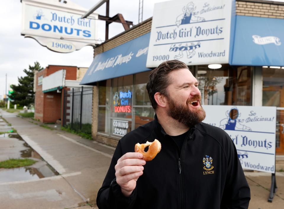 Paddy Lynch, owner of Dutch Girl Donuts in Detroit, eats a doughnut in front of the popular doughnut shop during the store’s soft opening on Friday, May 3, 2024.