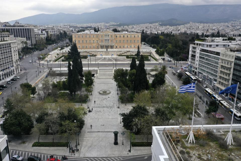 In this Wednesday, April 1, 2020 photo, a view of the virtually empty Syntagma square, with the Greek parliament in the background, in Athens. Deserted squares, padlocked parks, empty avenues where cars were once jammed bumper-to-bumper in heavy traffic. The Greek capital, like so many cities across the world, has seen its streets empty as part of a lockdown designed to stem the spread of the new coronavirus. (AP Photo/Thanassis Stavrakis)