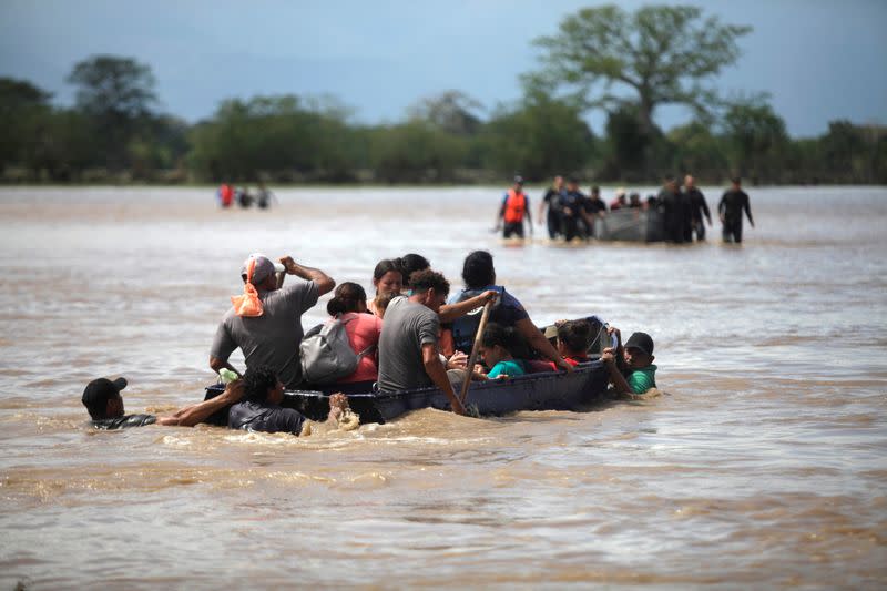 FILE PHOTO: Flood-affected people get on a boat to cross a street after passage of Storm Eta, in La Lima