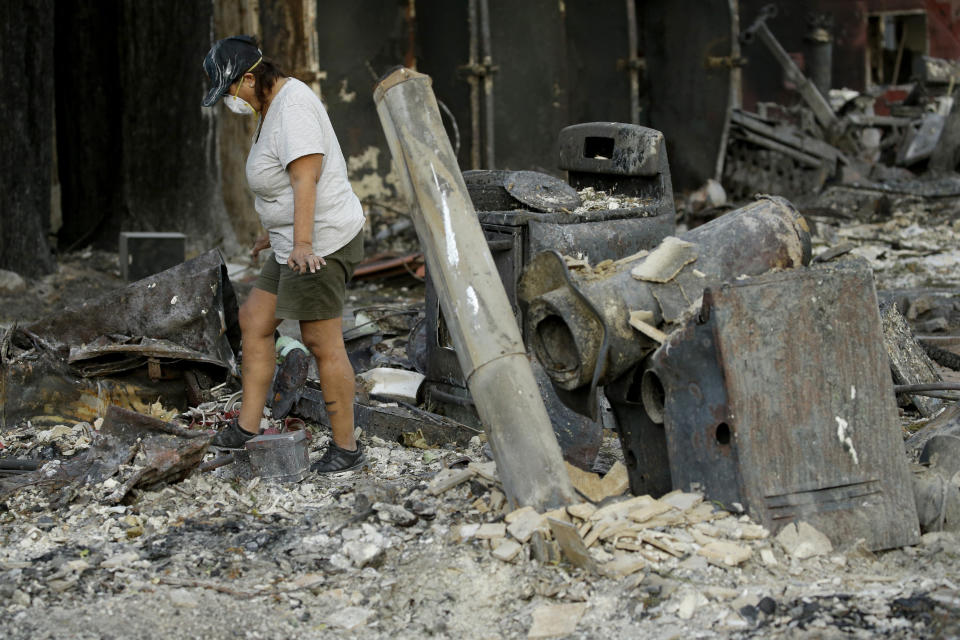 Bernadette Laos looks for salvageable items in her home that was destroyed by the Kincade Fire near Geyserville, Calif., Thursday, Oct. 31, 2019. (AP Photo/Charlie Riedel)