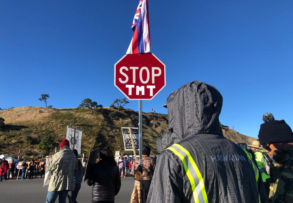 Demonstrators gather to block a road at the base of Hawaii's tallest mountain, Monday, July 15, 2019, in Mauna Kea, Hawaii, to protest the construction of a giant telescope on land that some Native Hawaiians consider sacred. (AP Photo/Caleb Jones)