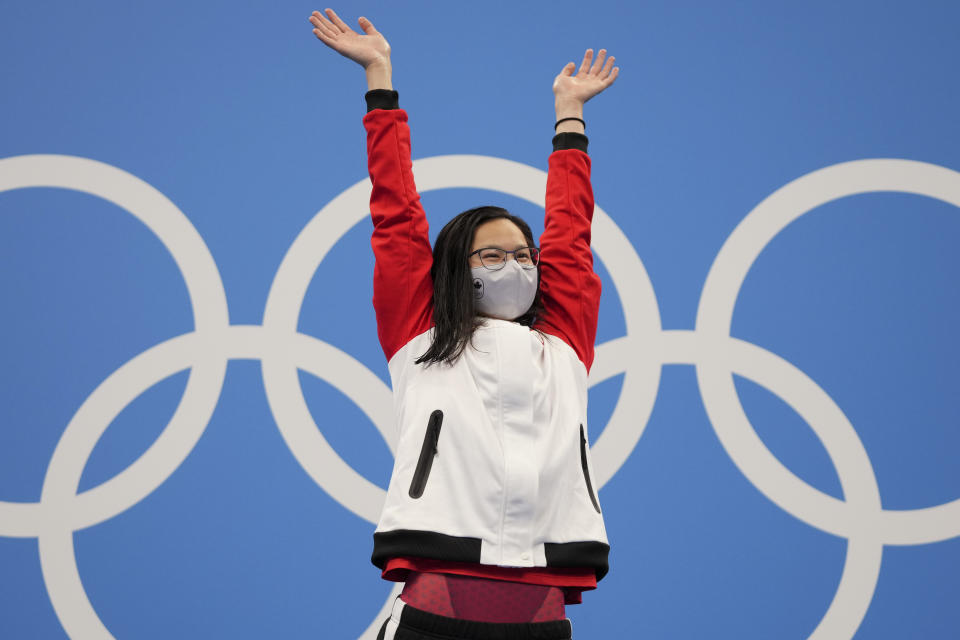 Margaret MacNeil of Canada celebrates on the podium after winning the women's 100-meter butterfly final at the 2020 Summer Olympics, Monday, July 26, 2021, in Tokyo, Japan. (AP Photo/Matthias Schrader)