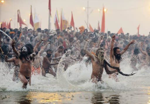Sadhus or holy men run into the Sangham, the confluence of the the Yamuna, Ganges and mythical Sarawati rivers, during the Kumbh Mela in Allahabad on January 14, 2013. The Kumbh Mela, celebrated every 12 years at the conjunction of two sacred rivers on the outskirts of the northern Indian city of Allahabad, drew massive crowds of devotees, ascetics and foreign tourists
