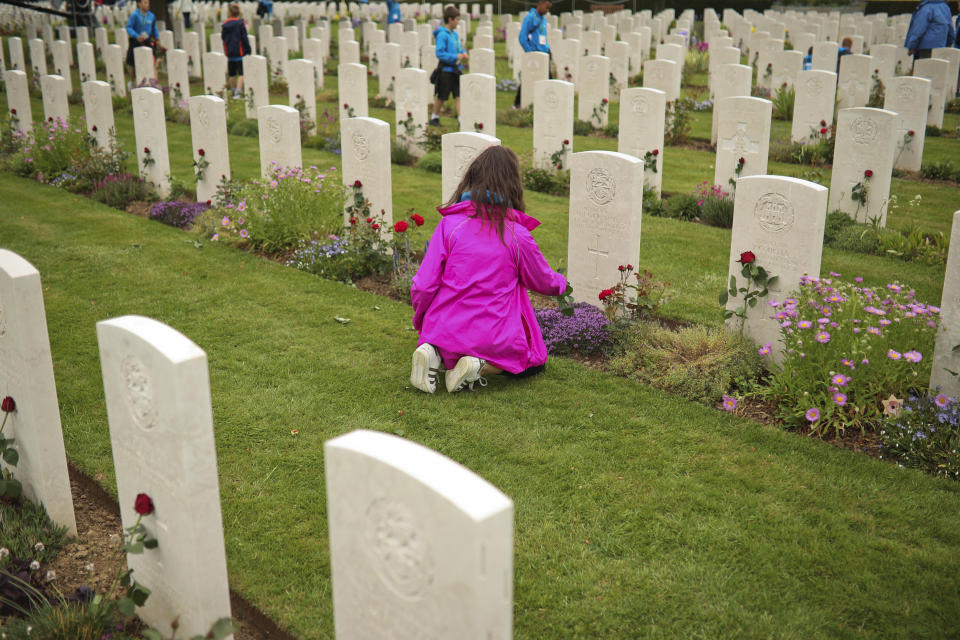 A young girl places a flower in a British soldier burial fallen during the WWII at the Bayeux War cemetery in Bayeux, Normandy region of France, Wednesday, June 5, 2019. Extensive commemorations are being held in the U.K. and France to honor the nearly 160,000 troops from Britain, the United States, Canada and other nations who landed in Normandy on June 6, 1944 in history's biggest amphibious invasion. (AP Photo/Francisco Seco)