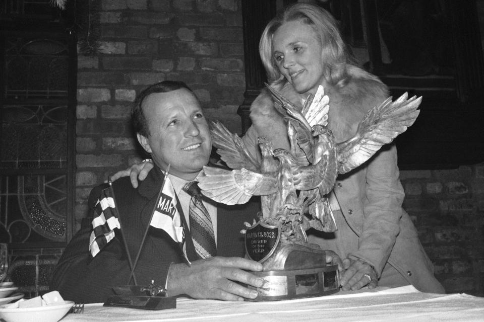 FILE - A.J. Foyt, accompanied by his wife, Lucy, sits with the Martini and Rossi golden eagles trophy for the American auto race driver of the year which he received in New York on Dec. 15, 1975. (AP Photo/Harry Harris, File)