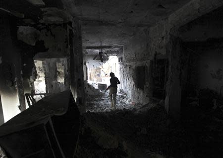 A Free Syrian Army fighter holding a weapon walks inside a damaged house in Deir al-Zor, eastern Syria November 14, 2013. REUTERS/Khalil Ashawi