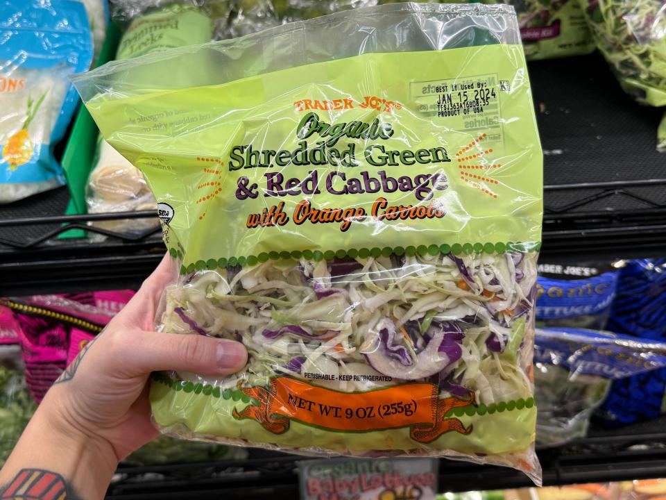 hand holding up a bag of shredded cabbage mix at trader joes