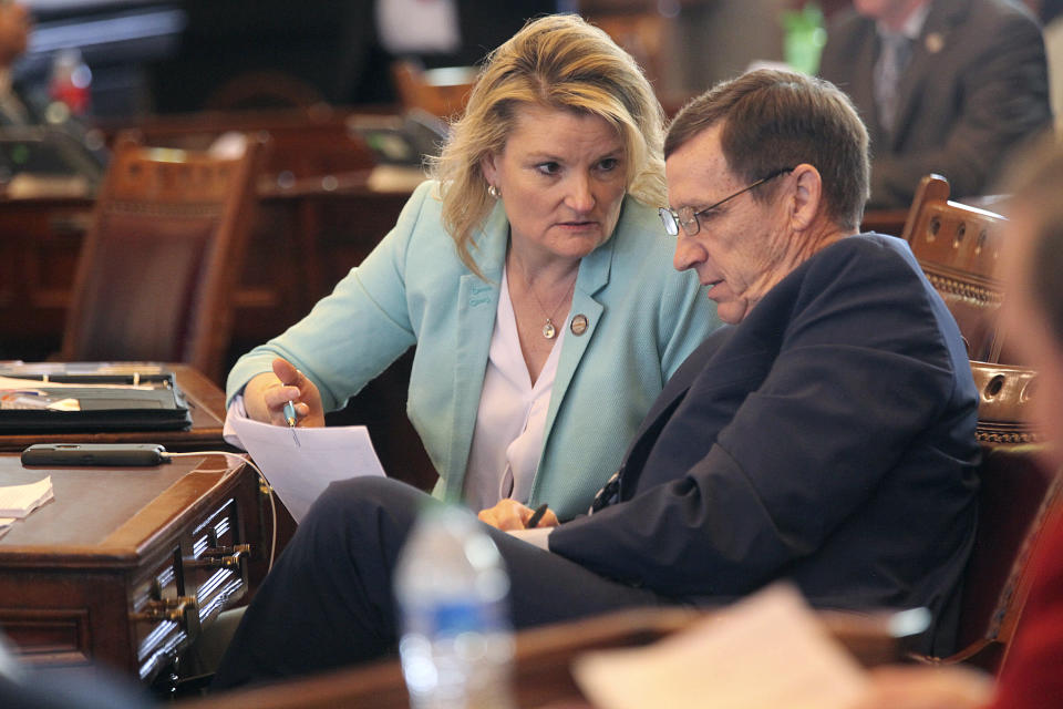 Kansas state Sen. Cindy Holscher, left, D-Overland Park, confers with Sen. Dennis Pyle, right, R-Hiawatha, during the Senate's debate on a bill that would cut state income, sales and property taxes, Thursday, April 4, 2024, at the Statehouse in Topeka, Kan. Both senators support the measure, which was drafted by top Republican lawmakers and Democratic Gov. Laura Kelly. (AP Photo/John Hanna)