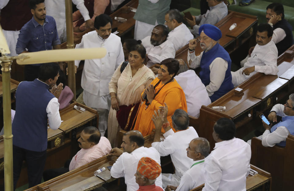 FILE- In this May 25, 2019 file photo, newly elected lawmaker Pragya Singh Thakur, center in orange dress, greets other lawmakers on her arrival at Bharatiya Janata Party parliamentary and their alliance meeting to elect Narendra Modi as their leader in New Delhi, India. Thakur, who won a seat from Bhopal in central India, is awaiting trial in connection with a 2008 explosion in Malegaon in western India that killed seven people. India's recent national election delivered a historic victory to Prime Minister Narendra Modi's Hindu nationalist party, but also exposed the influence of money, power and questionable morality on the world's largest democracy.(AP Photo/Manish Swarup, File)