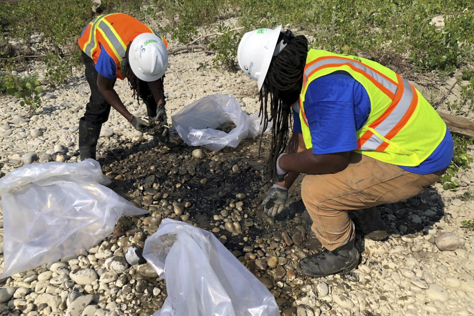 Cleanup workers pick through rocks as they try to remove oil products from an island along the Yellowstone River, Thursday, July 20, 2023, near Laurel, Mont. Most of the spilled material — a binder for asphalt that gets harder to handle as it warms — is expected to get left behind. (AP Photo/Matthew Brown)
